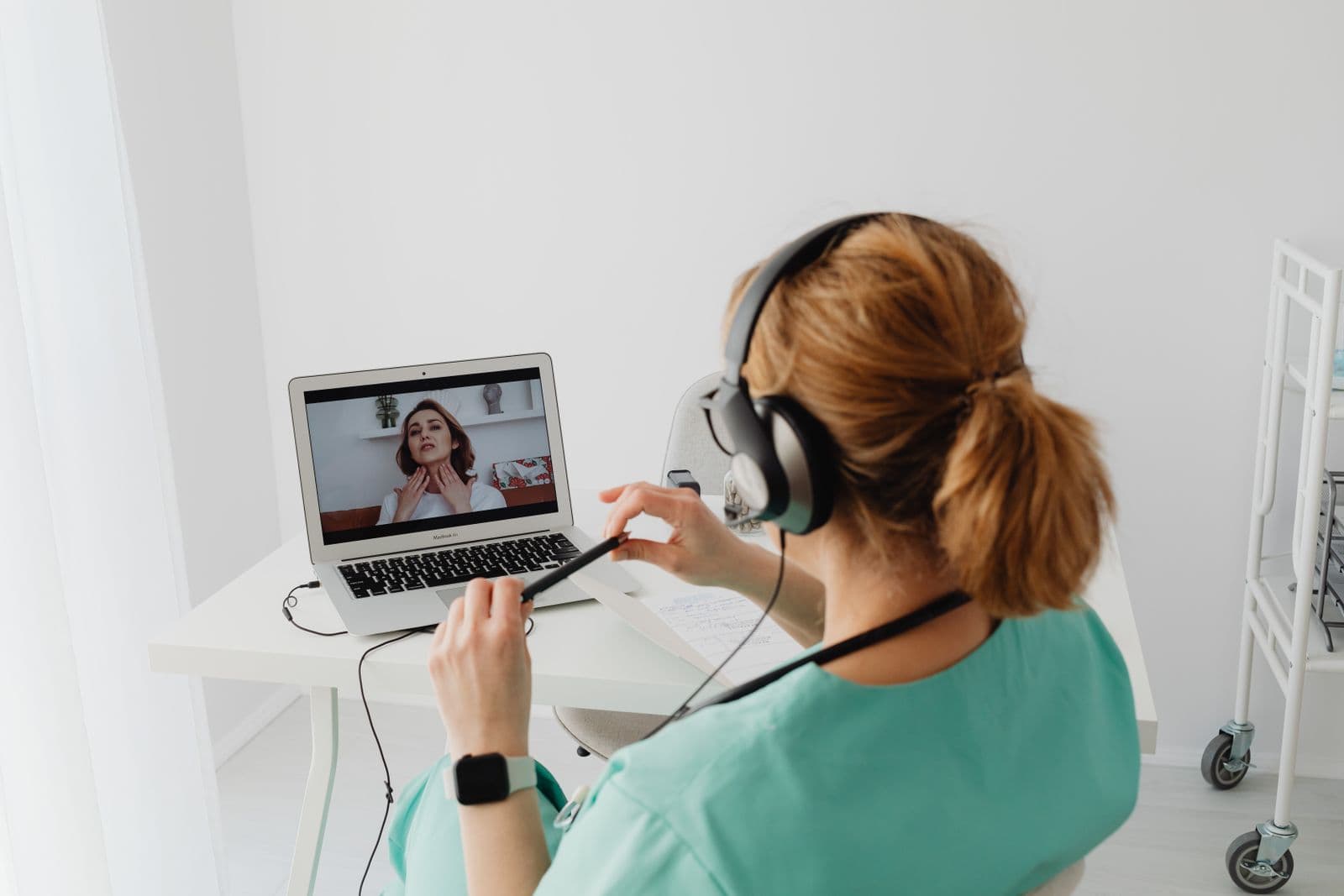 Healthcare provider with stethoscope conducting a telehealth visit at a computer workstation