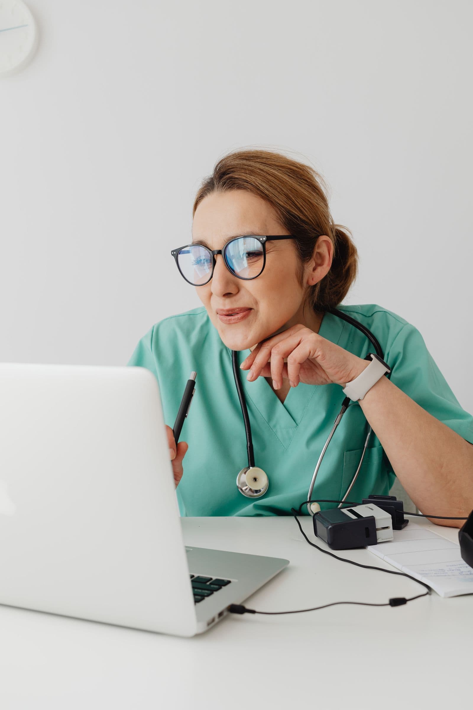 Provider at a desk reviewing vitals with an automatic blood pressure cuff, stethoscope, and digital workstation